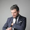 Businessman in formal attire adjusting his suit with confidence in a studio setting.